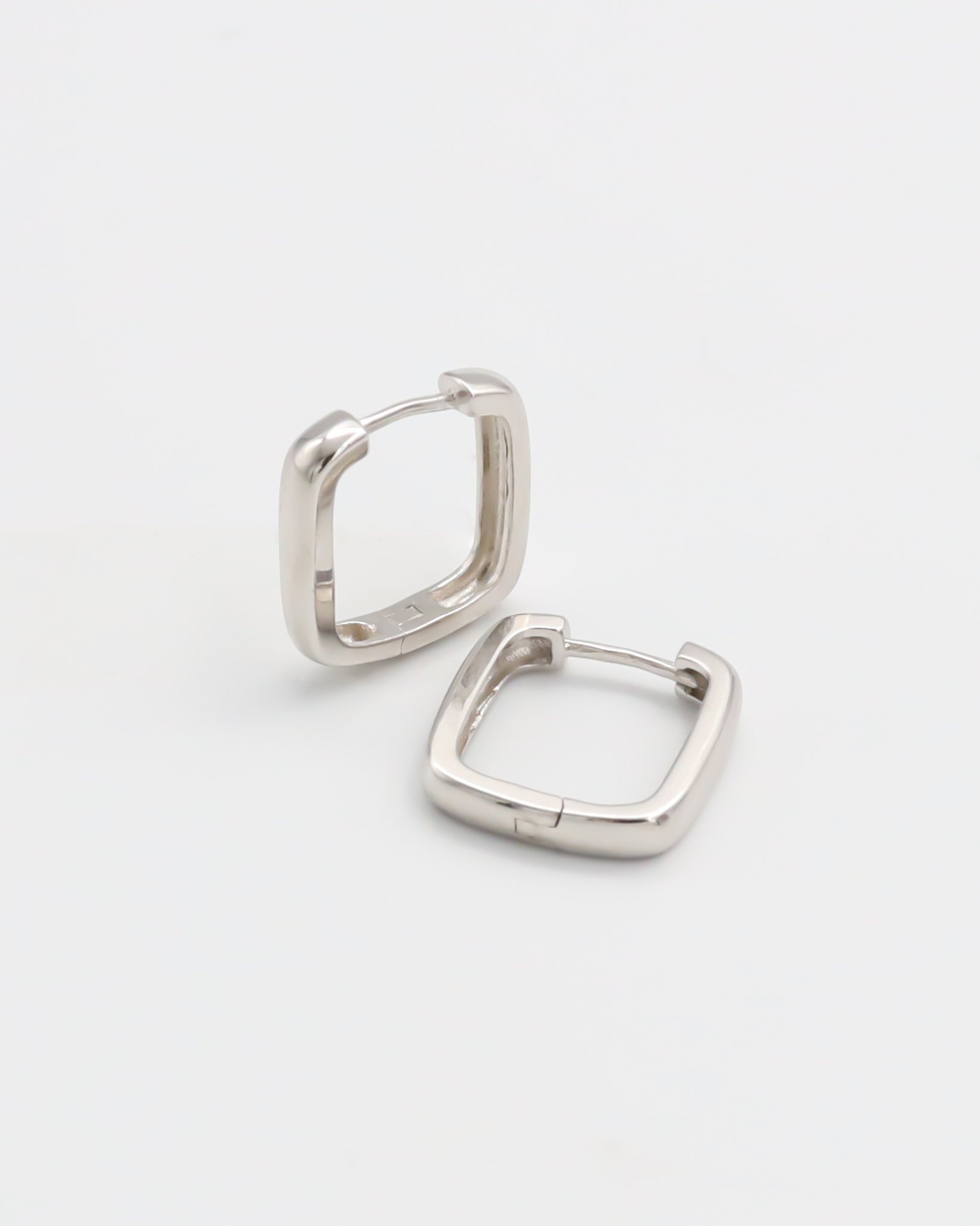 A pair of silver-colored hoop earrings with a hinged clasp, displayed against a white background.