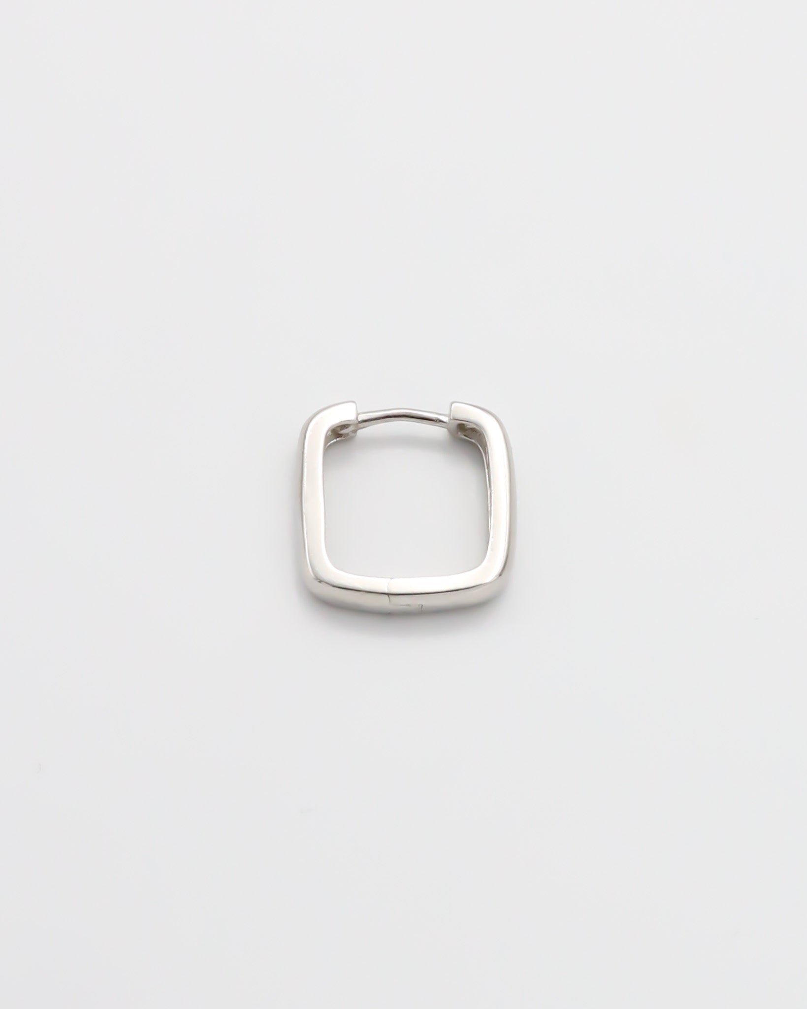A single silver-colored hoop earrings with a hinged clasp, displayed against a white background.