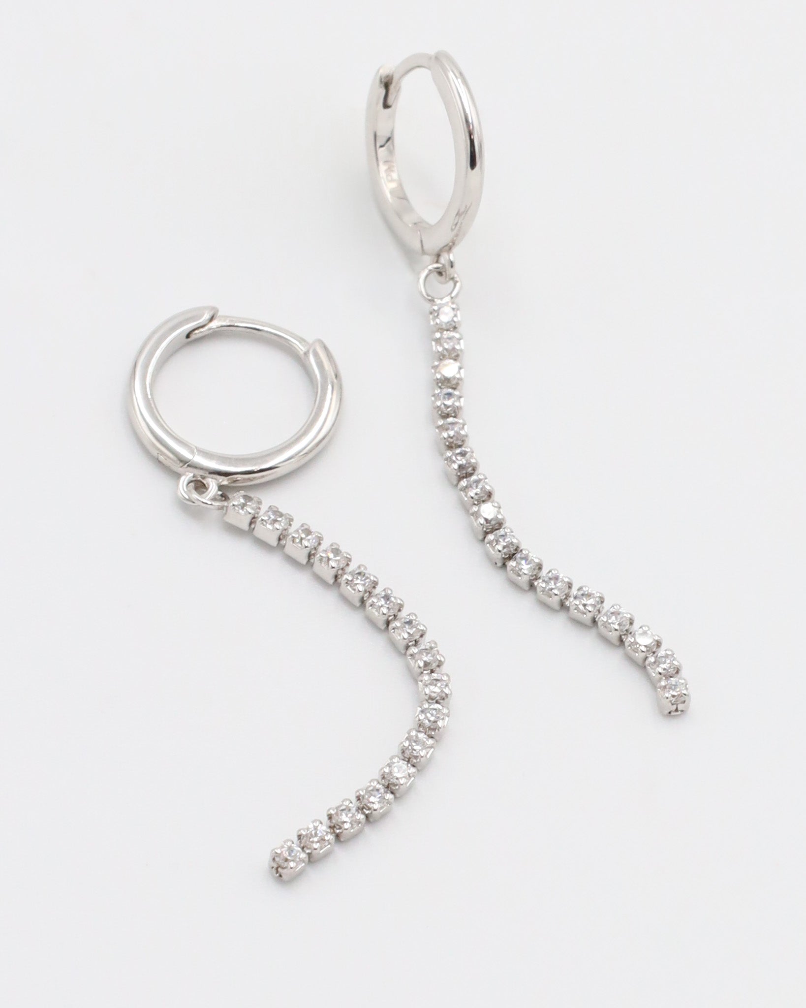 A silver hoop earring with a hinged clasp and small hanging diamonds