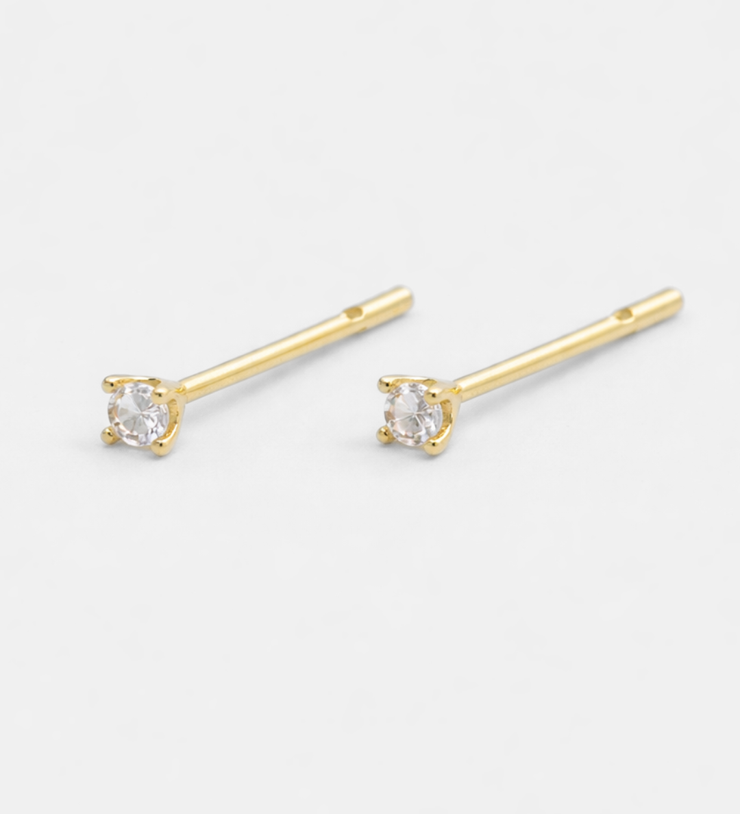 Gold stud earrings with clear gemstones on a white background