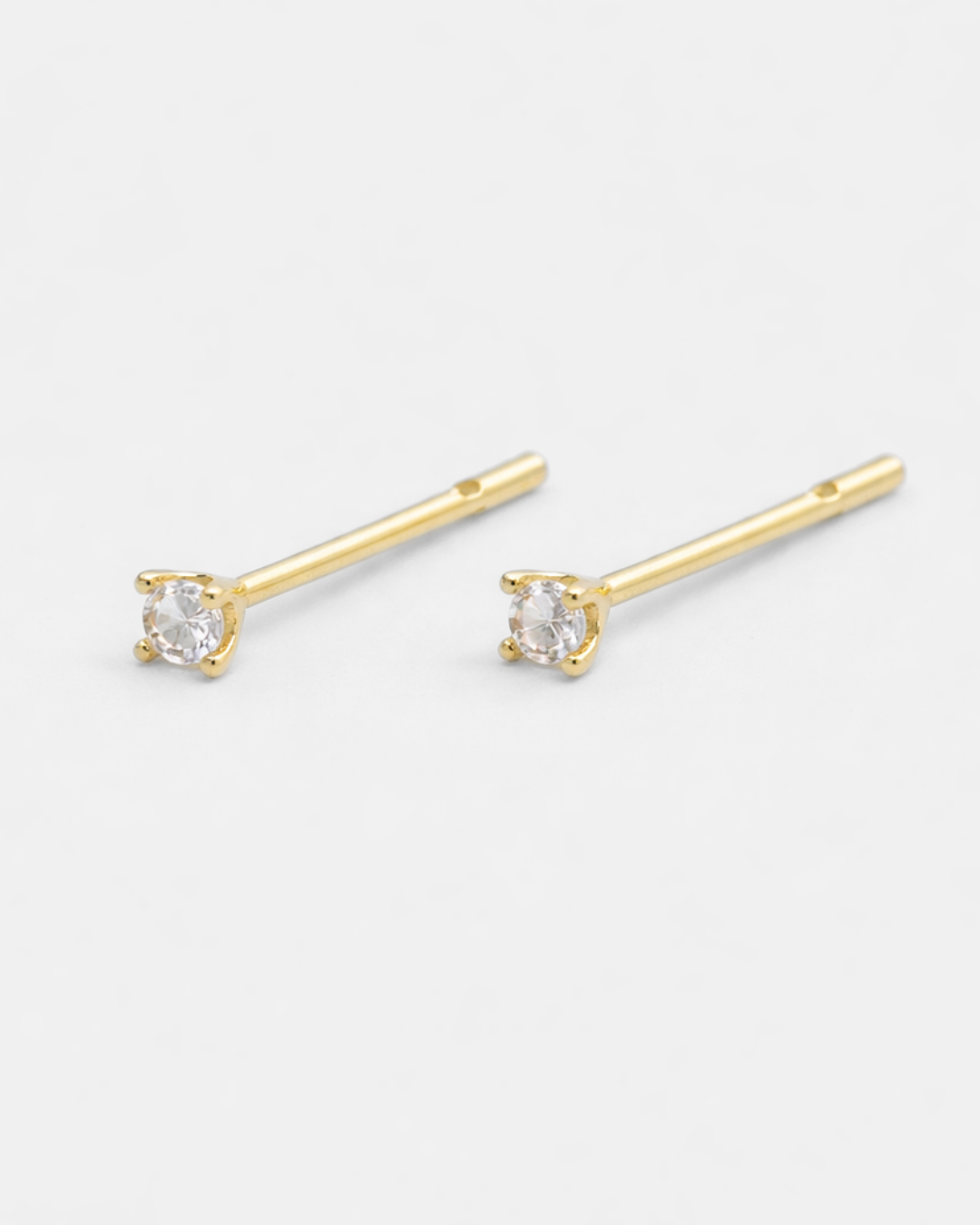 Gold stud earrings with clear gemstones on a white background