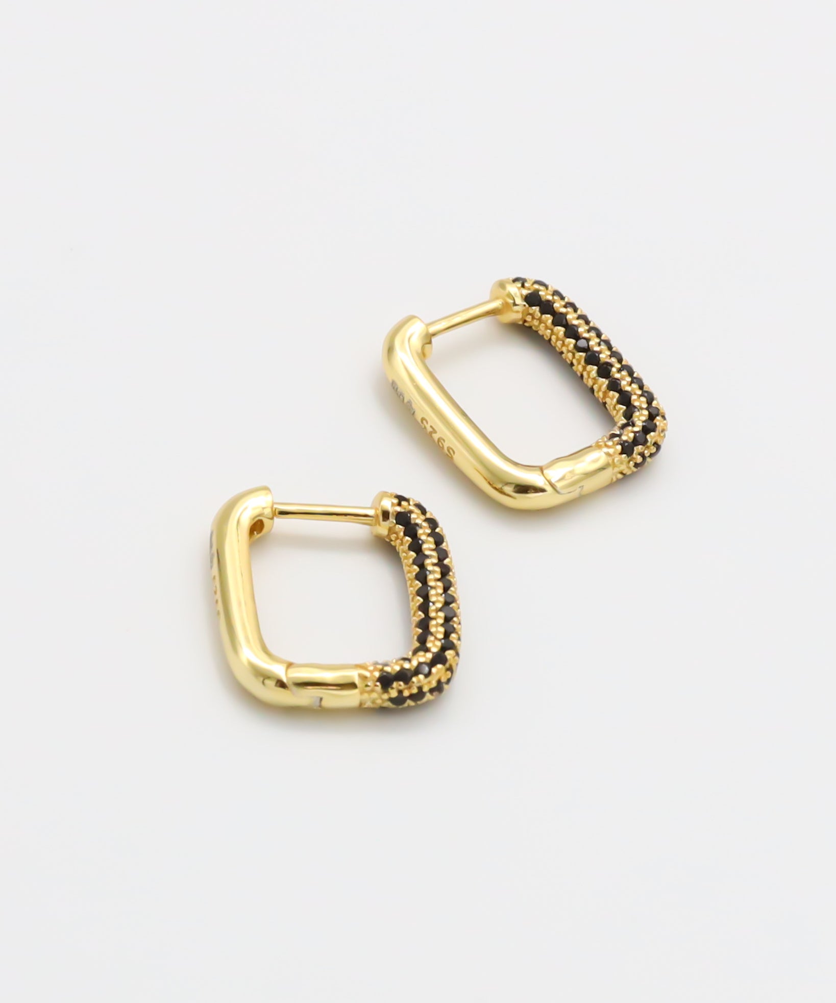 A single gold-colored hoop earring with black accents and a hinged clasp.