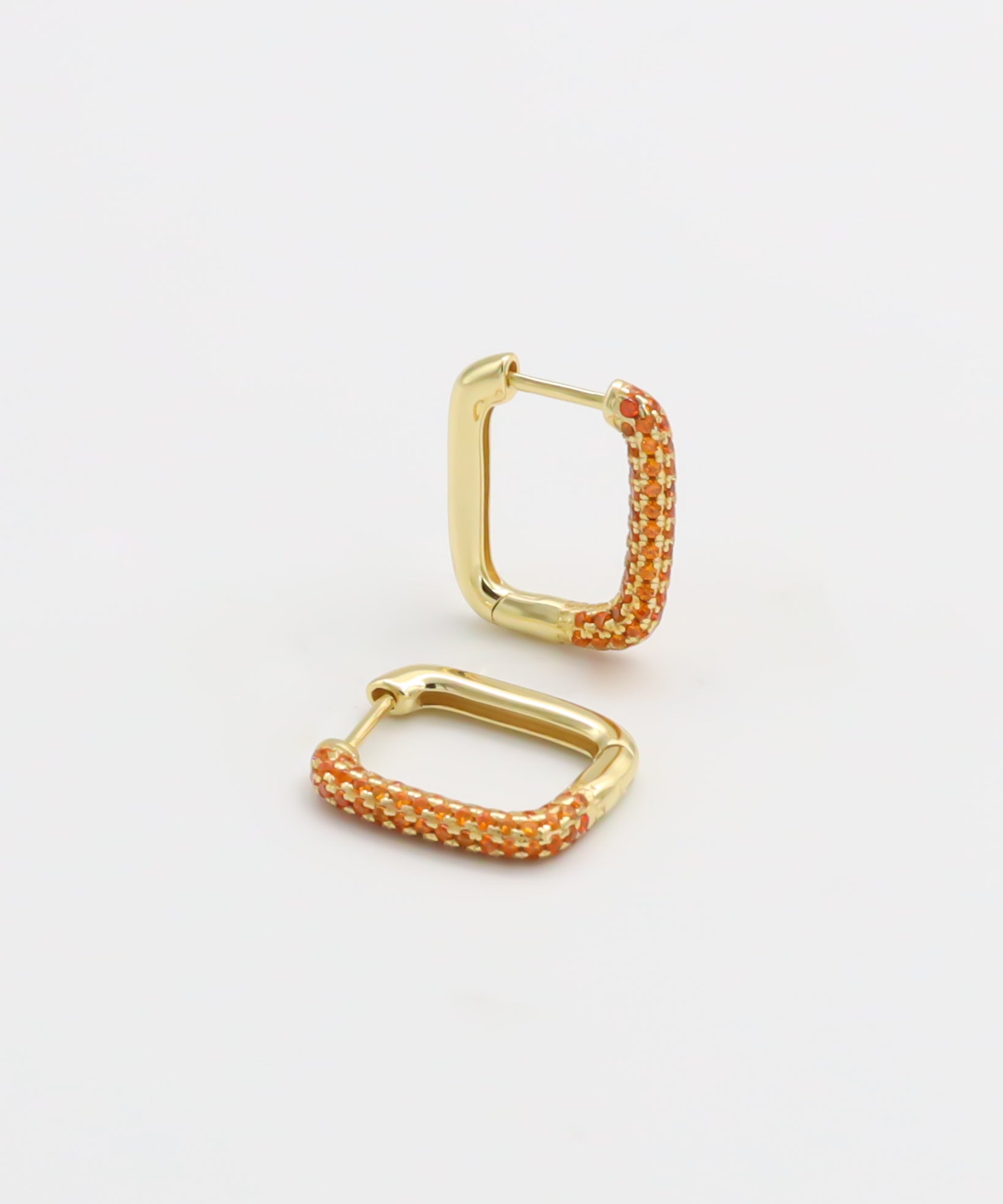 A gold-colored hoop earring with orange accents and a hinged clasp, displayed against a white background.