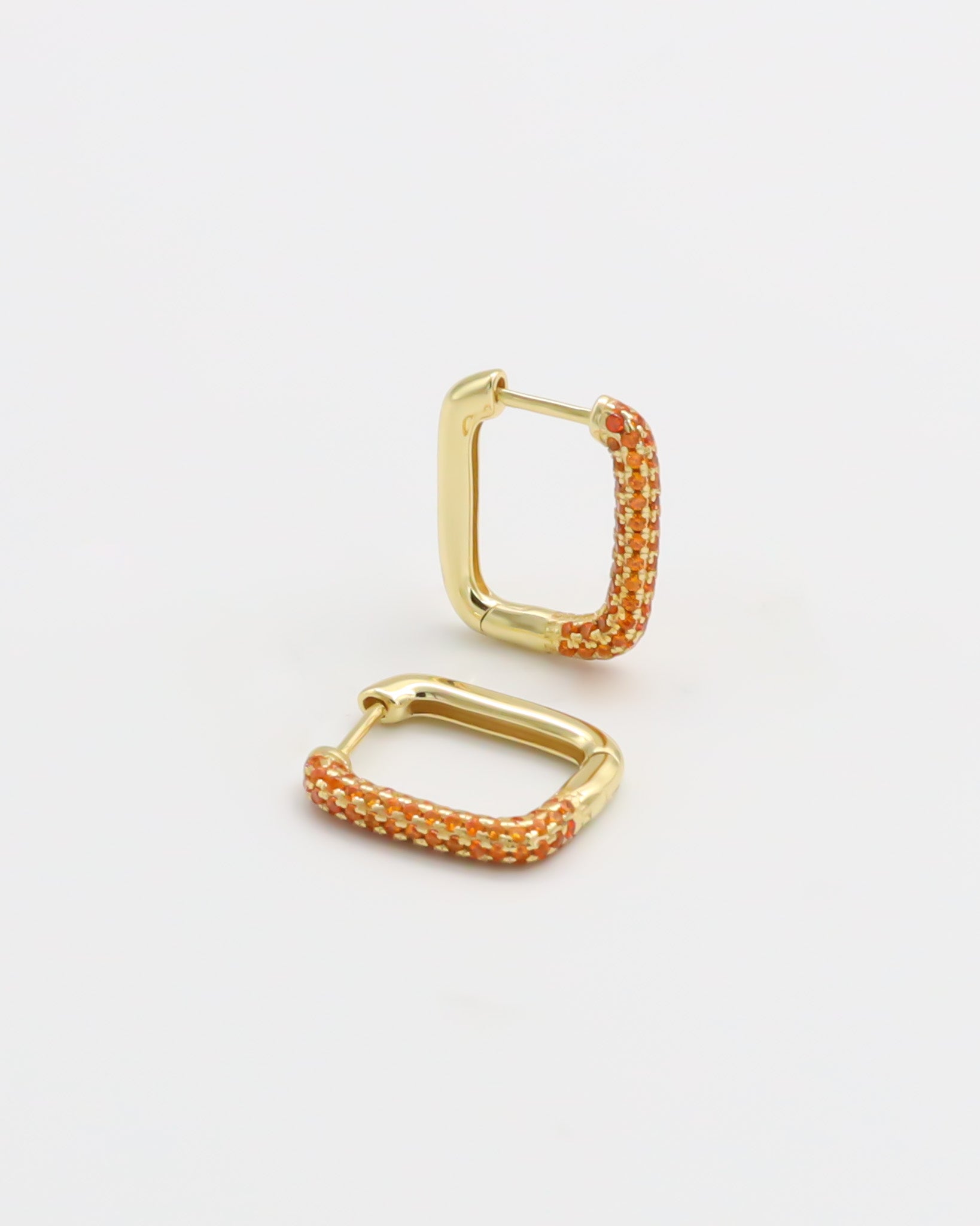 A gold-colored hoop earring with orange accents and a hinged clasp, displayed against a white background.