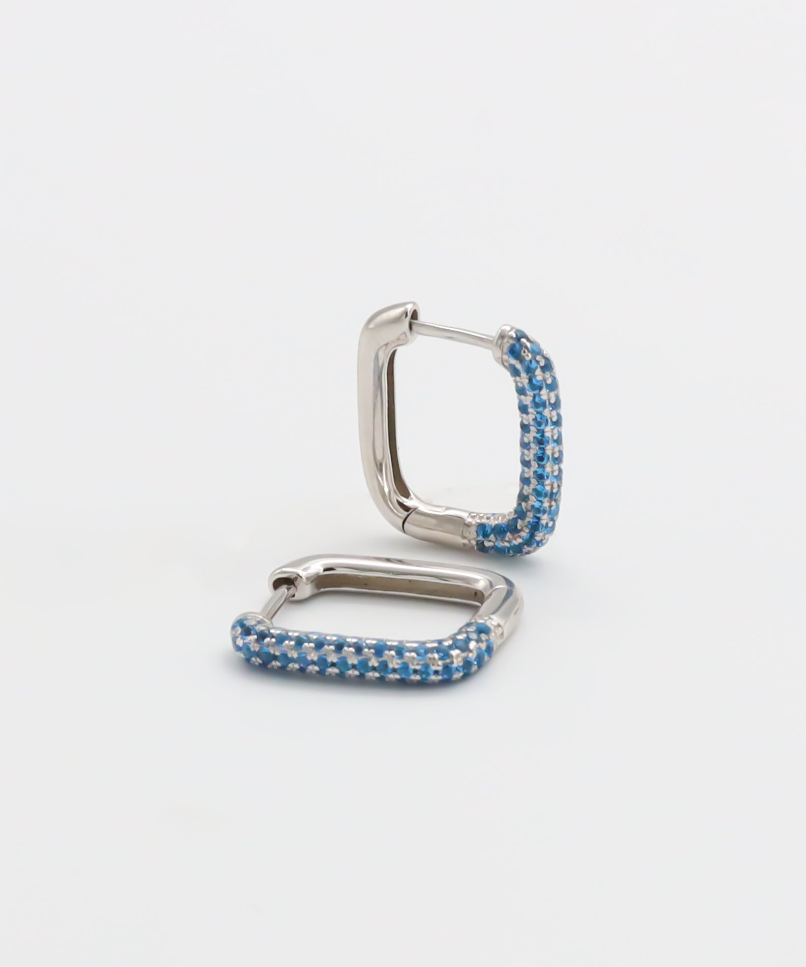 A silver hoop earring with blue accents, featuring a hinged closing mechanism.