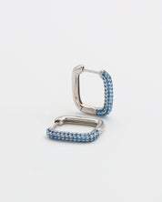A silver hoop earring with blue accents, featuring a hinged closing mechanism.