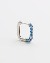 A silver hoop earring with blue accents, featuring a hinged closing mechanism.