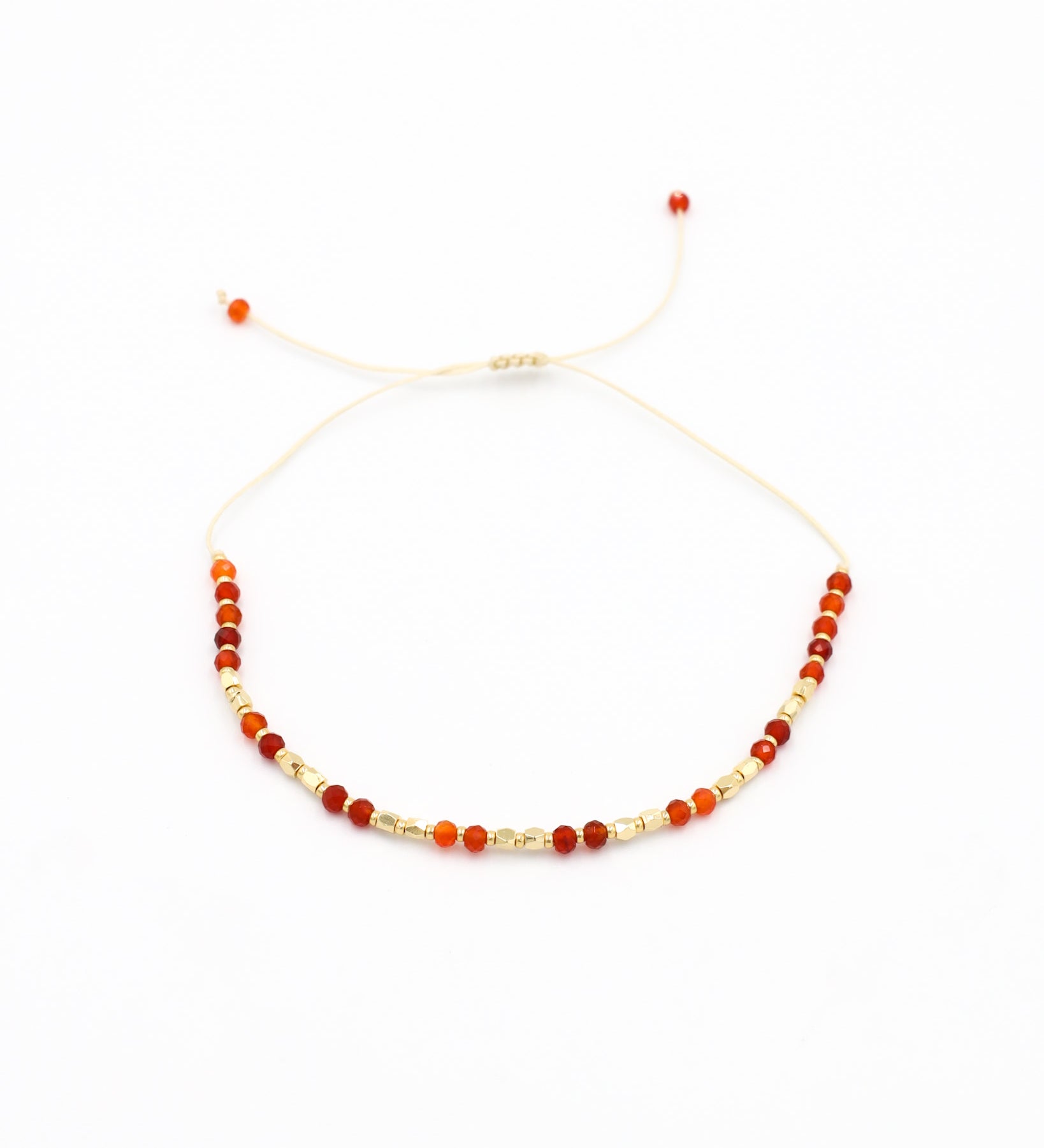 An adjustable beaded bracelet with a mix of gold and red beads and rhinestones.