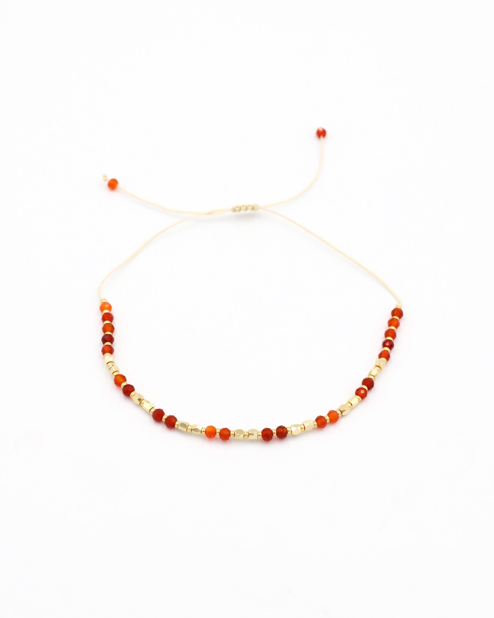 An adjustable beaded bracelet with a mix of gold and red beads and rhinestones.