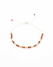 An adjustable beaded bracelet with a mix of gold and red beads and rhinestones.