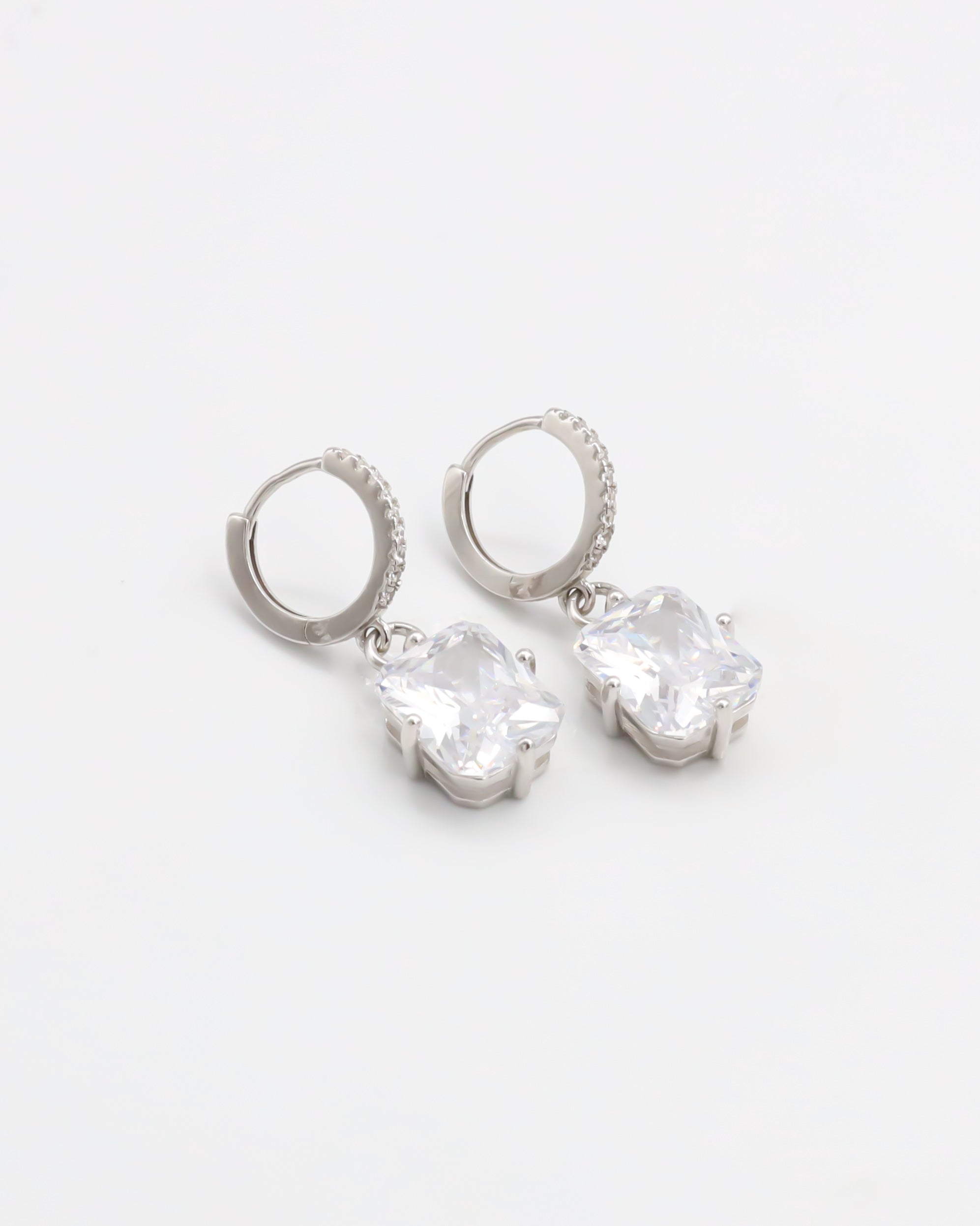 A pair of sterling silver hoop earrings with a hinged clasp and clear cubic zirconia stones.