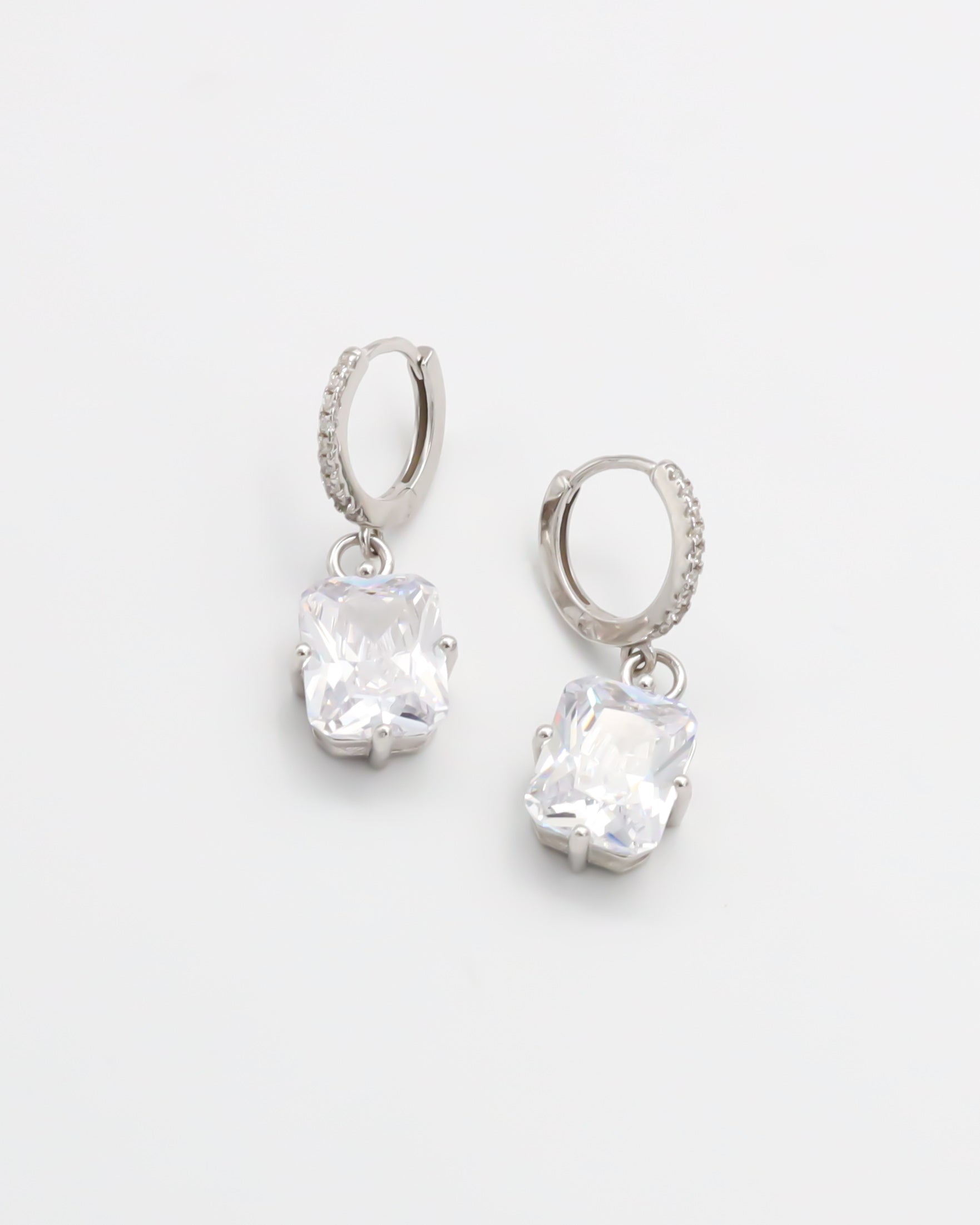 A pair of sterling silver hoop earrings with a hinged clasp and clear cubic zirconia stones.
