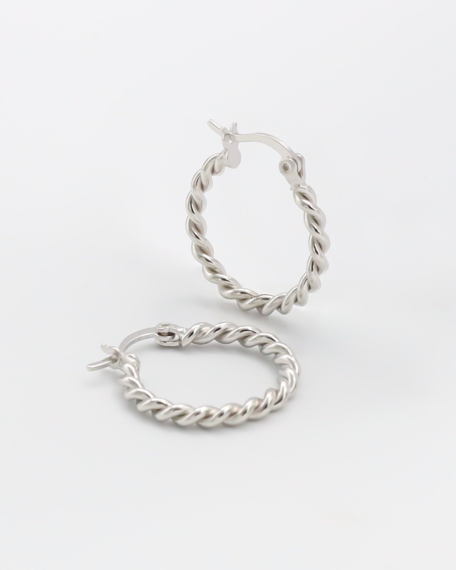 A pair of silver hoop earrings with a twist pattern and latch back clasps on a white background.