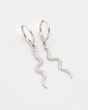 A silver hoop earring with a small silver charm shaped like a snake dangling from it.