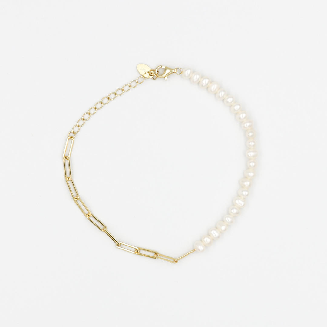 A two-tone gold bracelet with one half featuring smooth gold links and the other half with pearl beads, displayed against a white background.