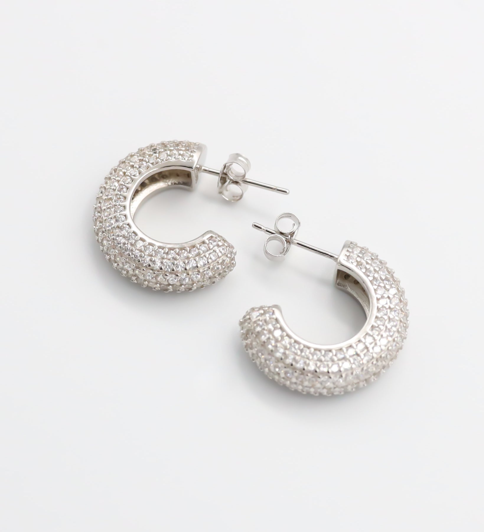 A pair of silver hoop earrings with a butterfly clasp closure.