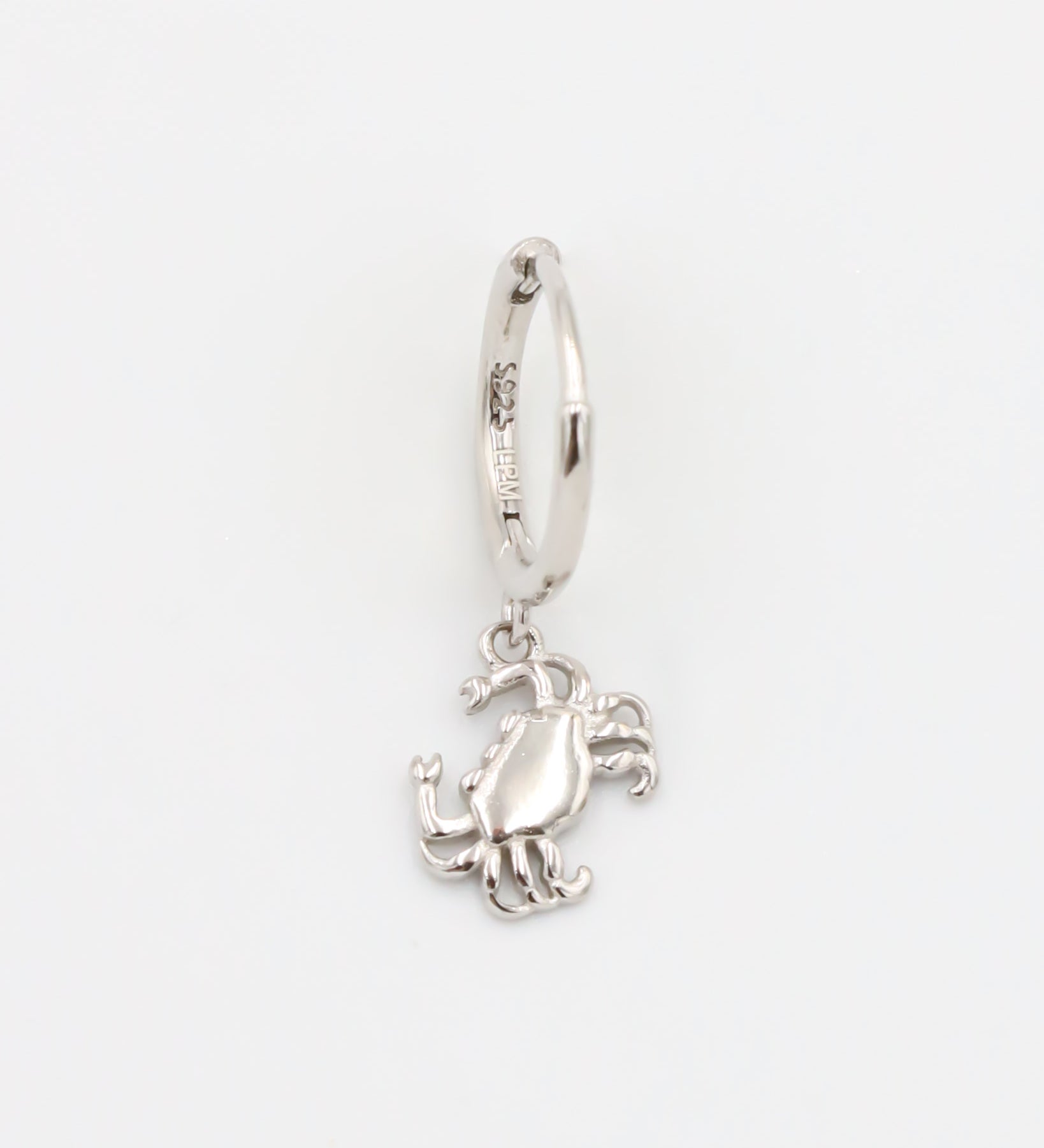 A silver-colored hoop earring with a crab charm attached to it.