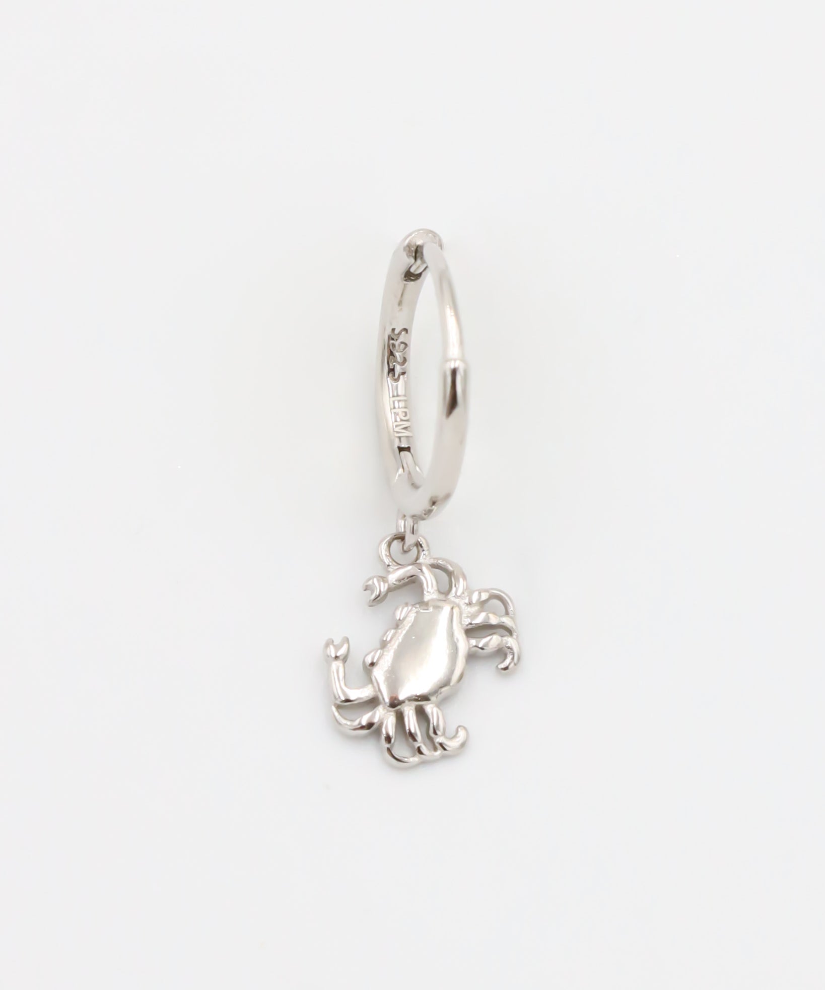 A silver-colored hoop earring with a crab charm attached to it.