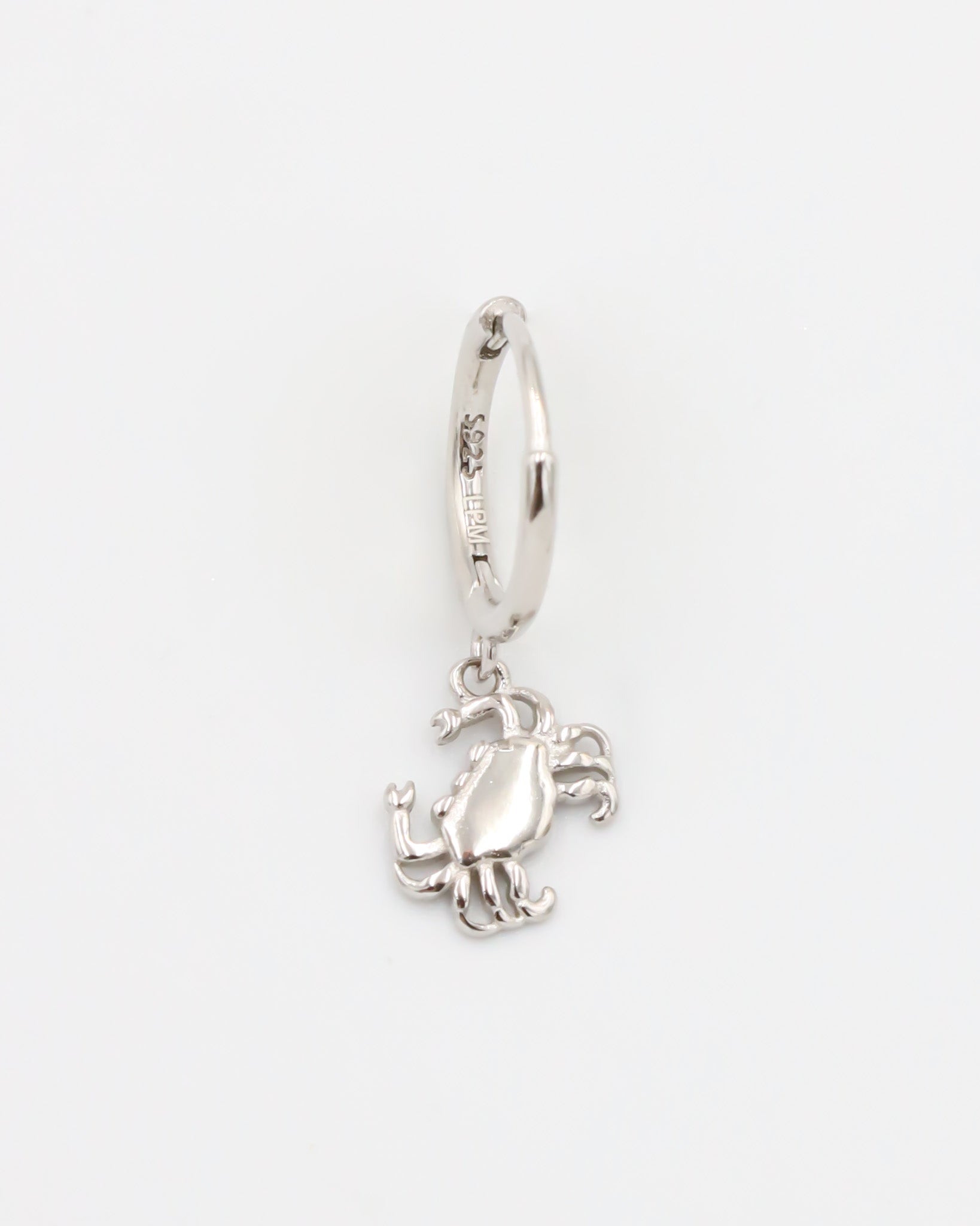 A silver-colored hoop earring with a crab charm attached to it.
