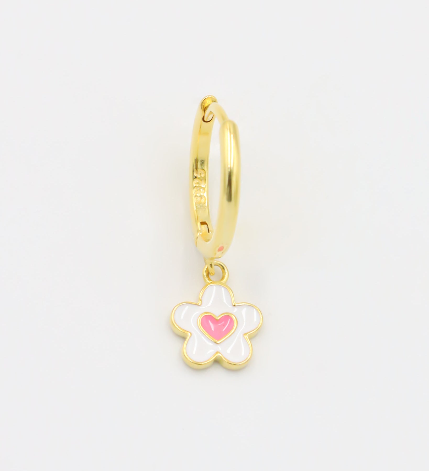 A gold-colored hoop earring with a white and gold flower-shaped charm attached to it.