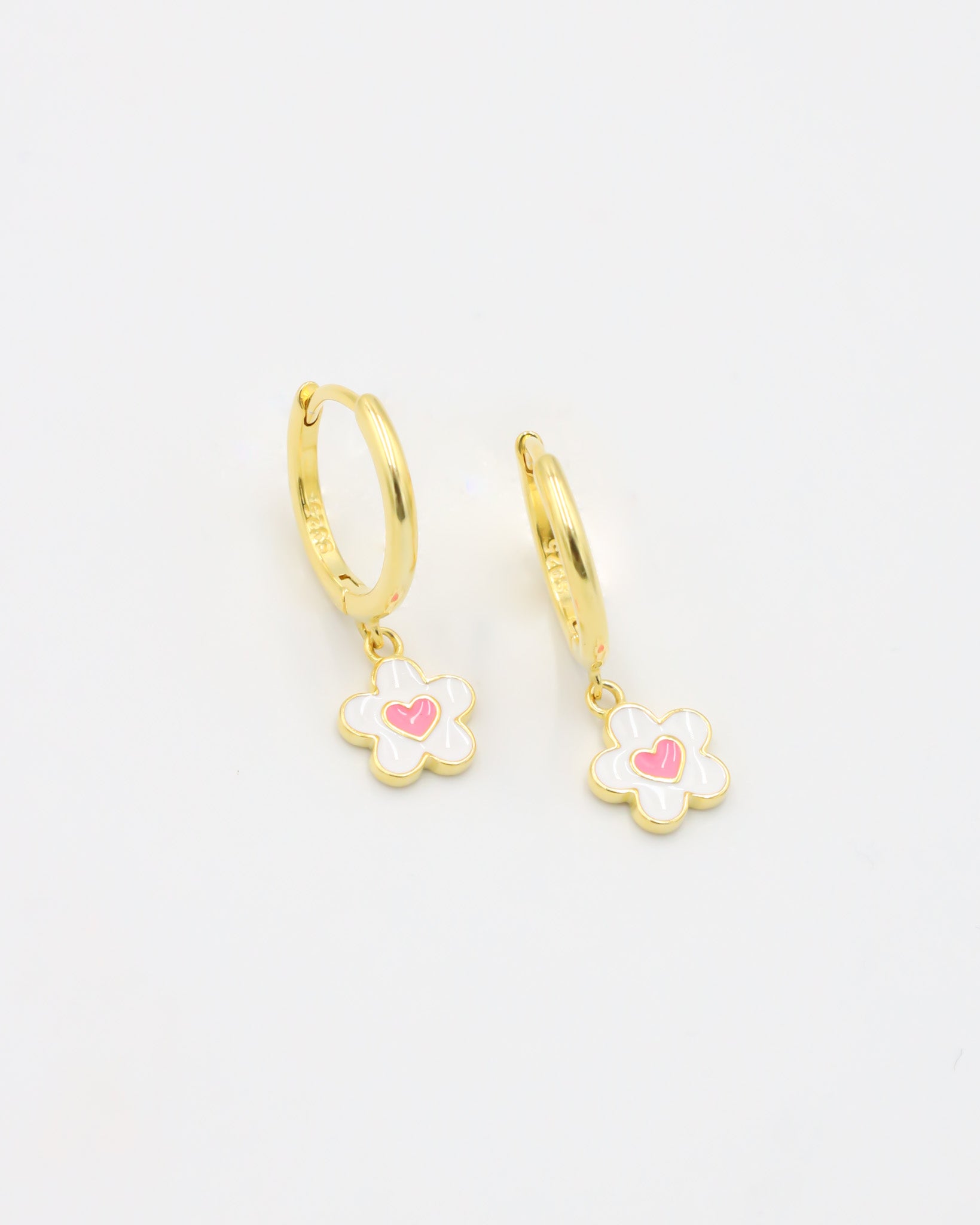 A gold-colored hoop earring with a white and gold flower-shaped charm attached to it.