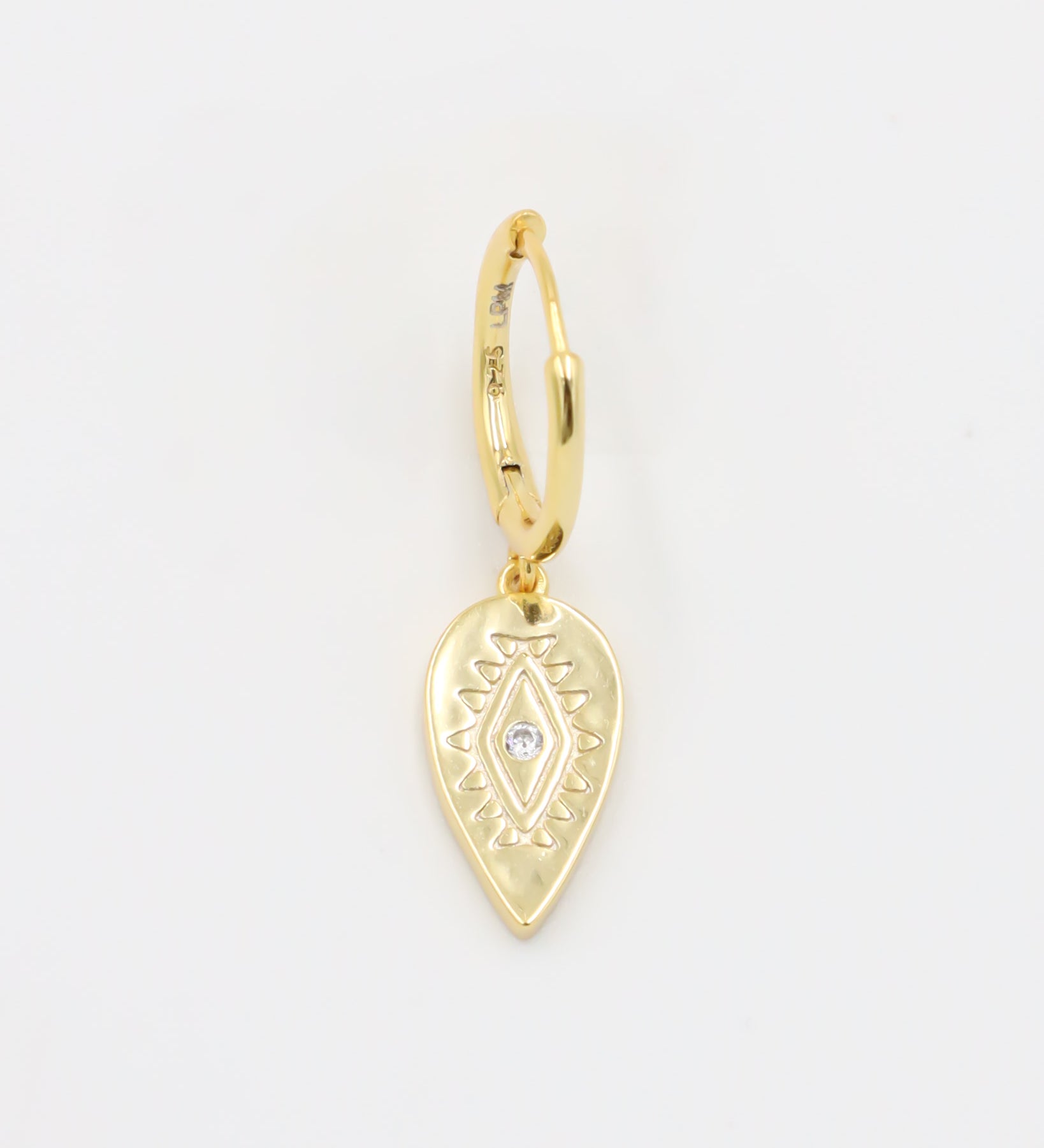 A single gold hoop earring with a hinged clasp and a dangling, ornate, gold heart-shaped charm.