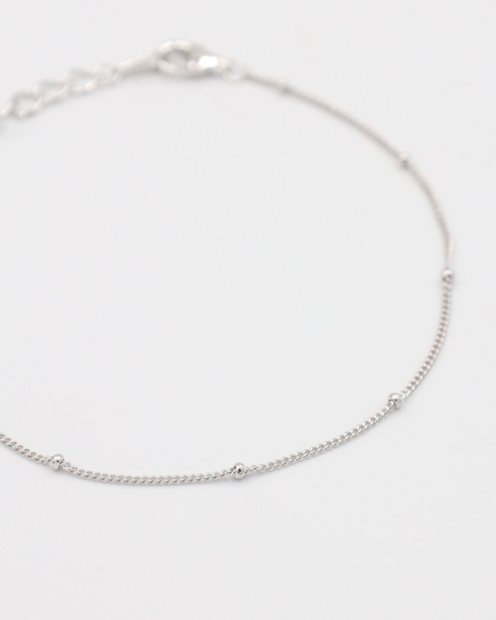 A silver bracelet with small spherical embellishments, displayed against a white background.