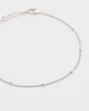 A silver bracelet with small spherical embellishments, displayed against a white background.