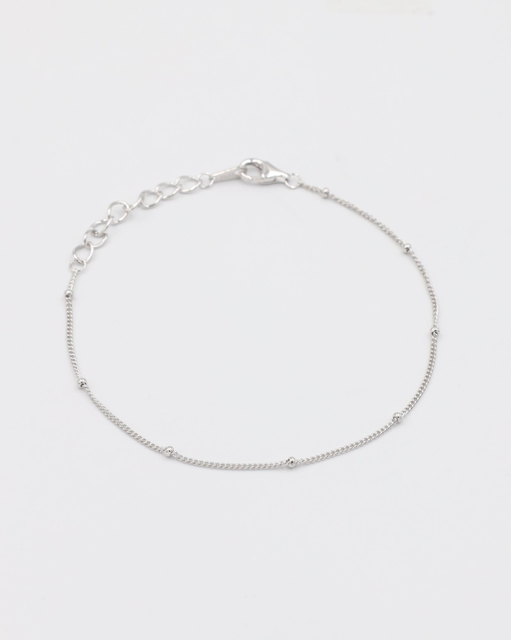 A silver bracelet with small spherical embellishments, displayed against a white background.