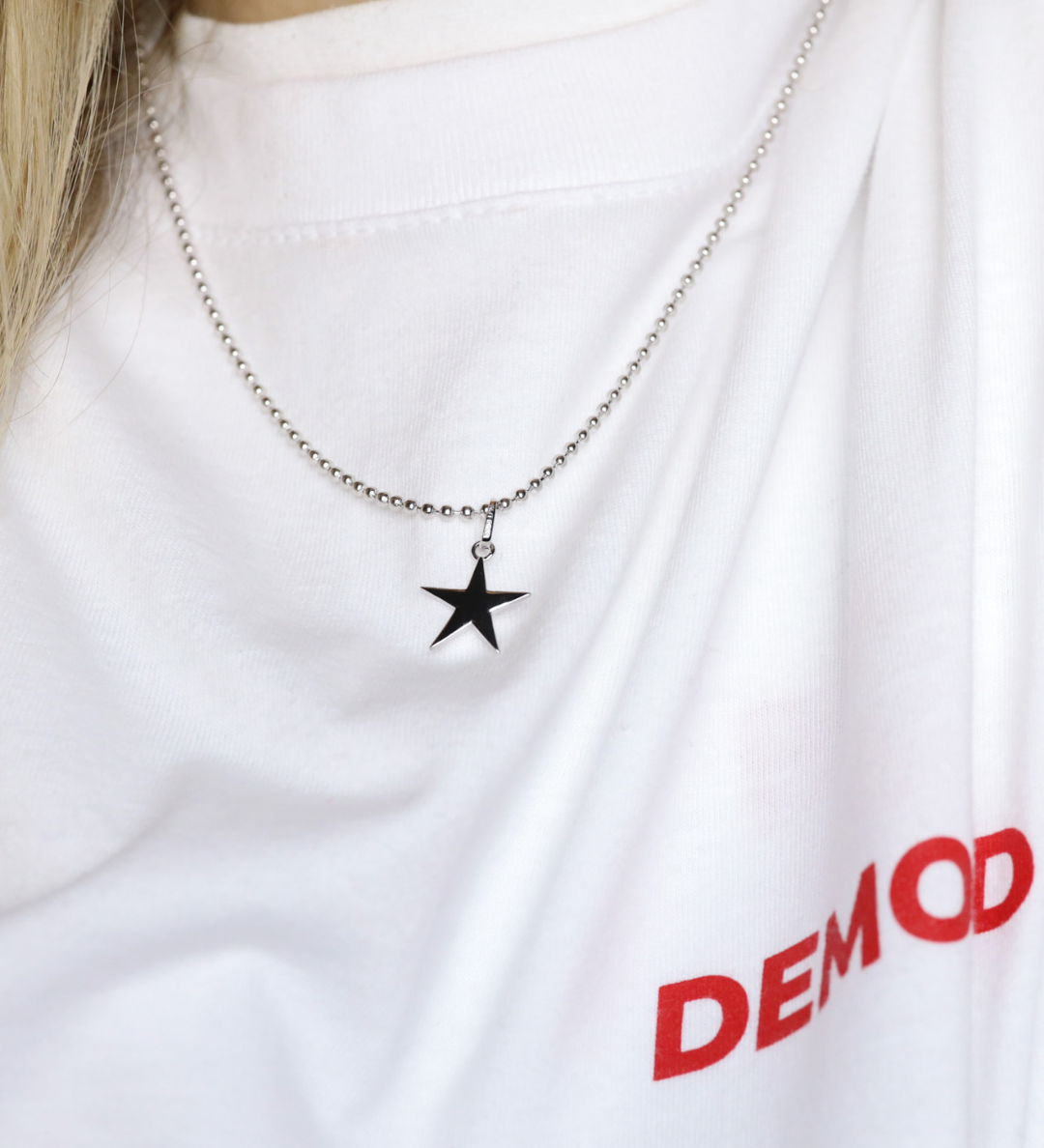Star pendant necklace on a white shirt with 'DEMOND' text