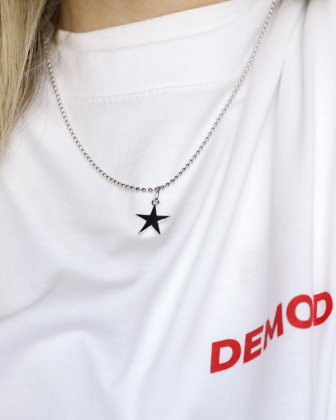 Star pendant necklace on a white shirt with 'DEMOND' text