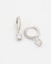 A silver hoop earring with a hinged clasp and a central gemstone, possibly a diamond, surrounded by smaller stones.
