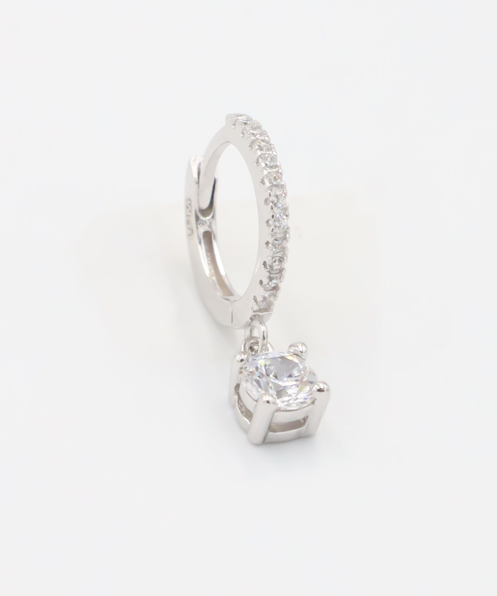 A silver hoop earring with a hinged clasp and a central gemstone, possibly a diamond, surrounded by smaller stones.
