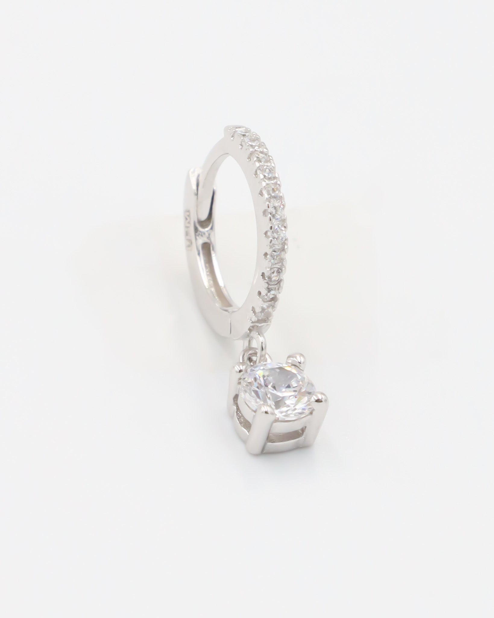 A silver hoop earring with a hinged clasp and a central gemstone, possibly a diamond, surrounded by smaller stones.
