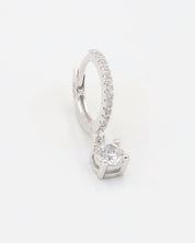 A silver hoop earring with a hinged clasp and a central gemstone, possibly a diamond, surrounded by smaller stones.