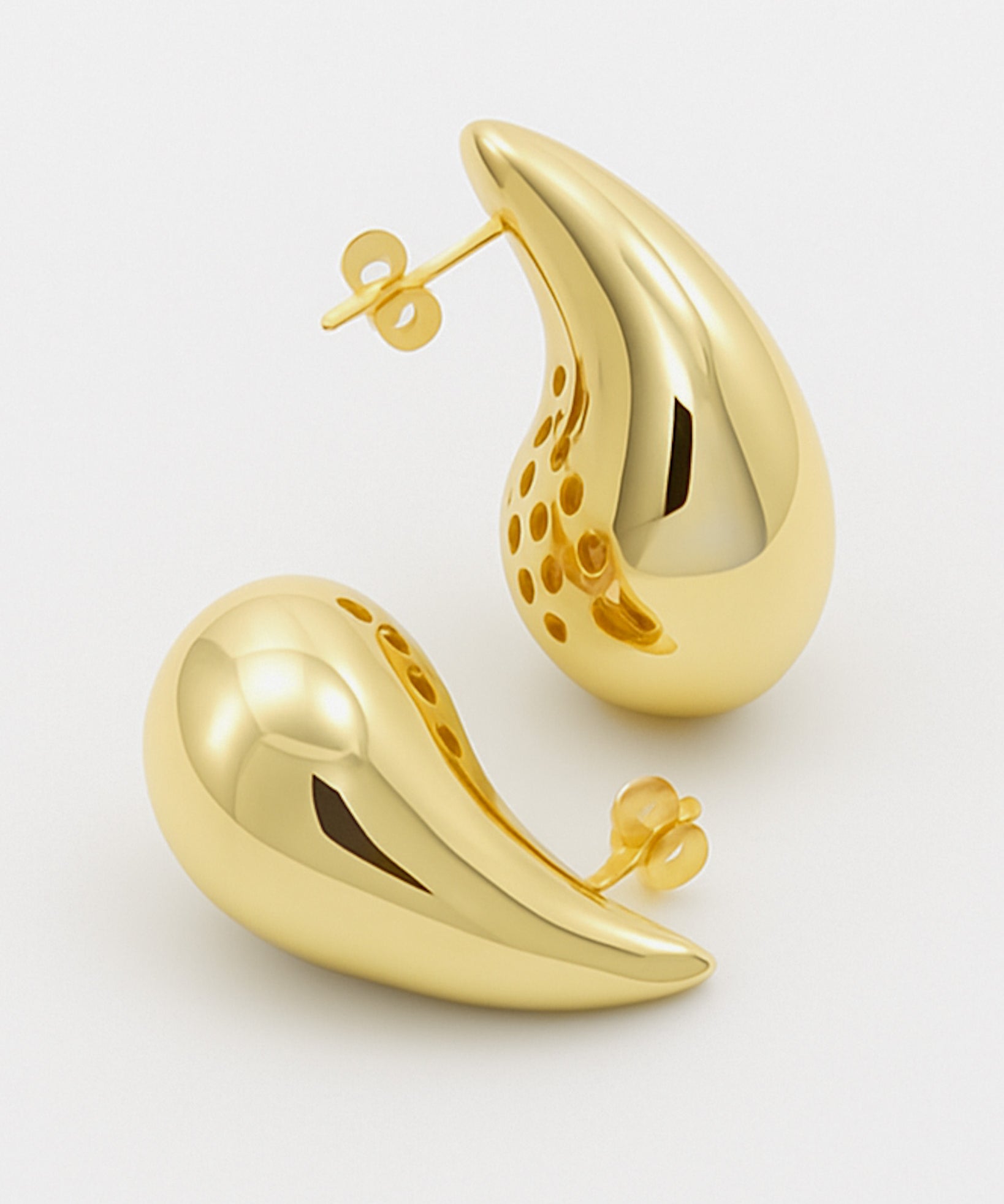 Gold earrings on a light gray background
