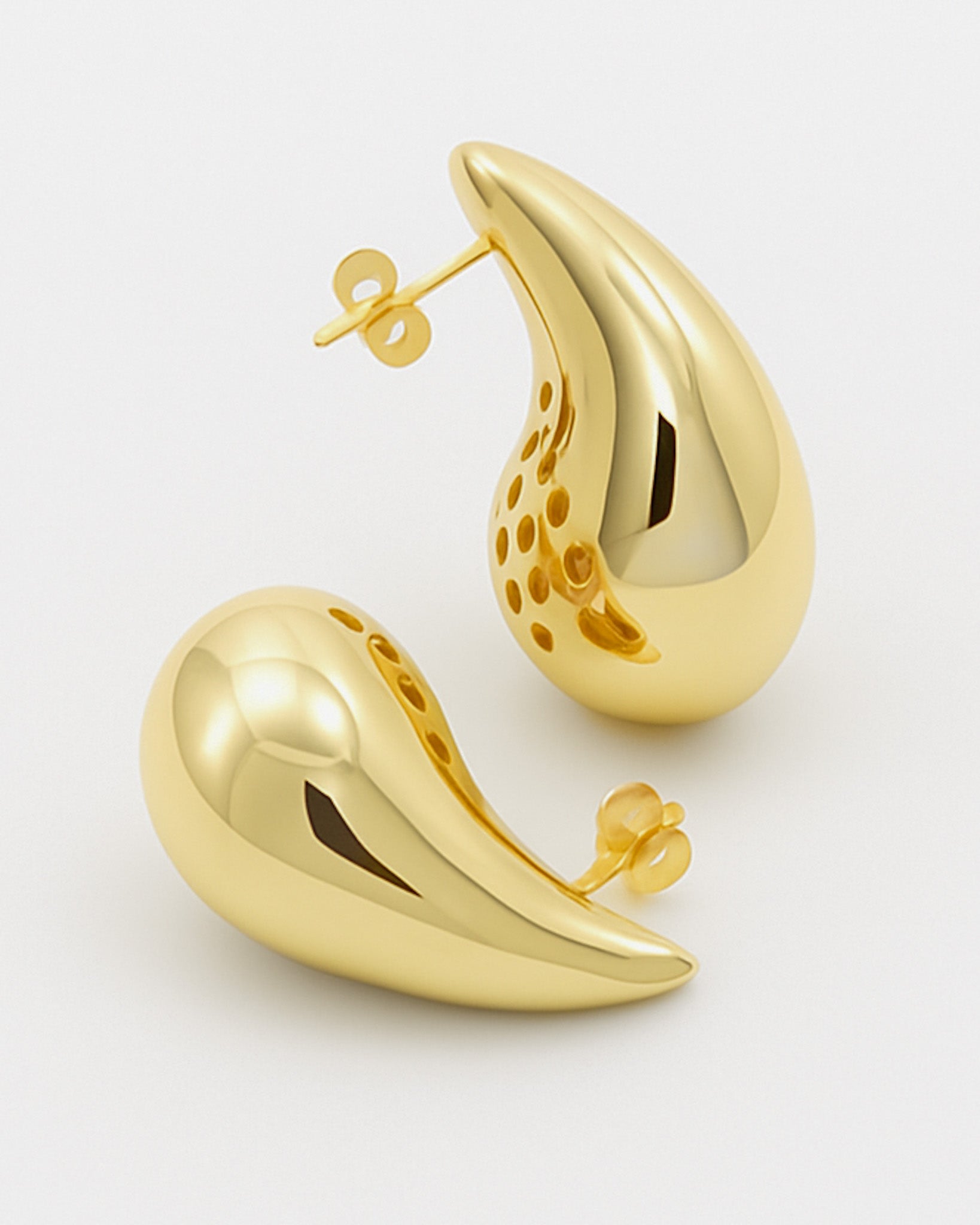 Gold earrings on a light gray background