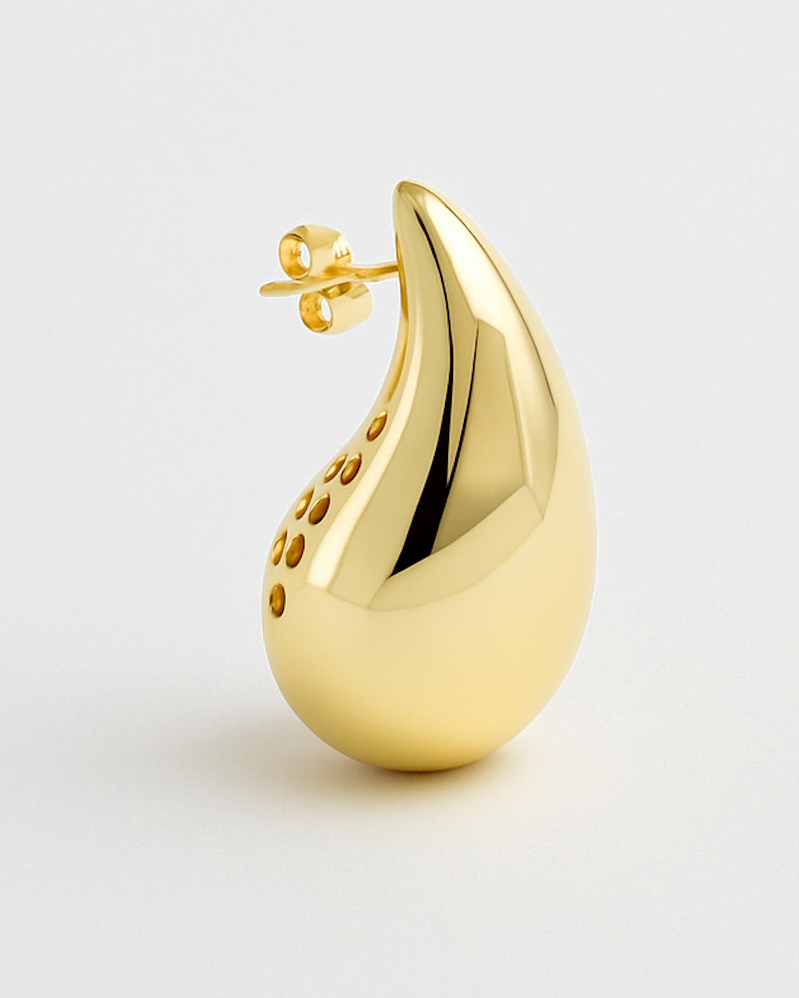 Gold teardrop-shaped earring on a light gray background