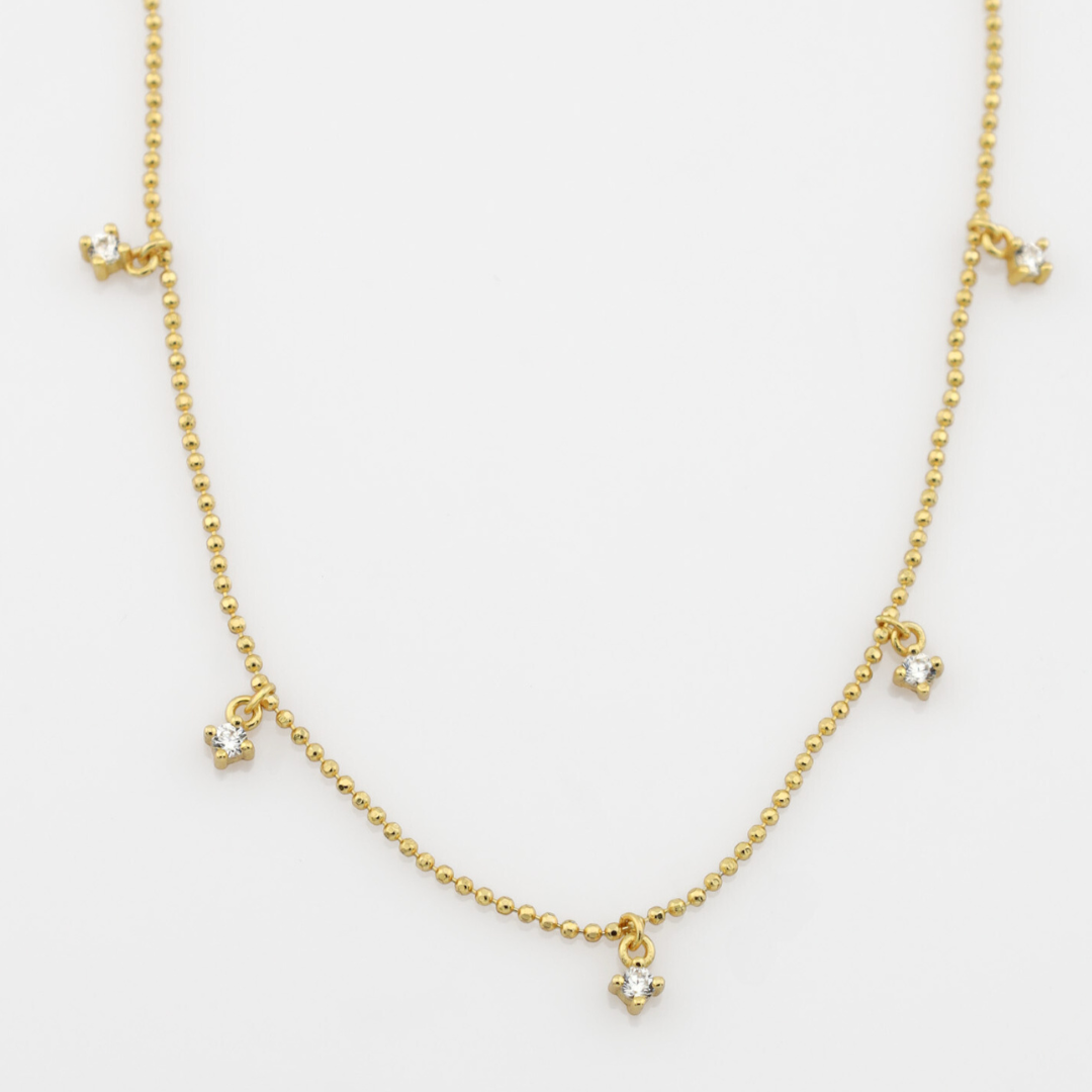 Gold necklace with small charms on a white background