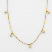 Gold necklace with small charms on a white background