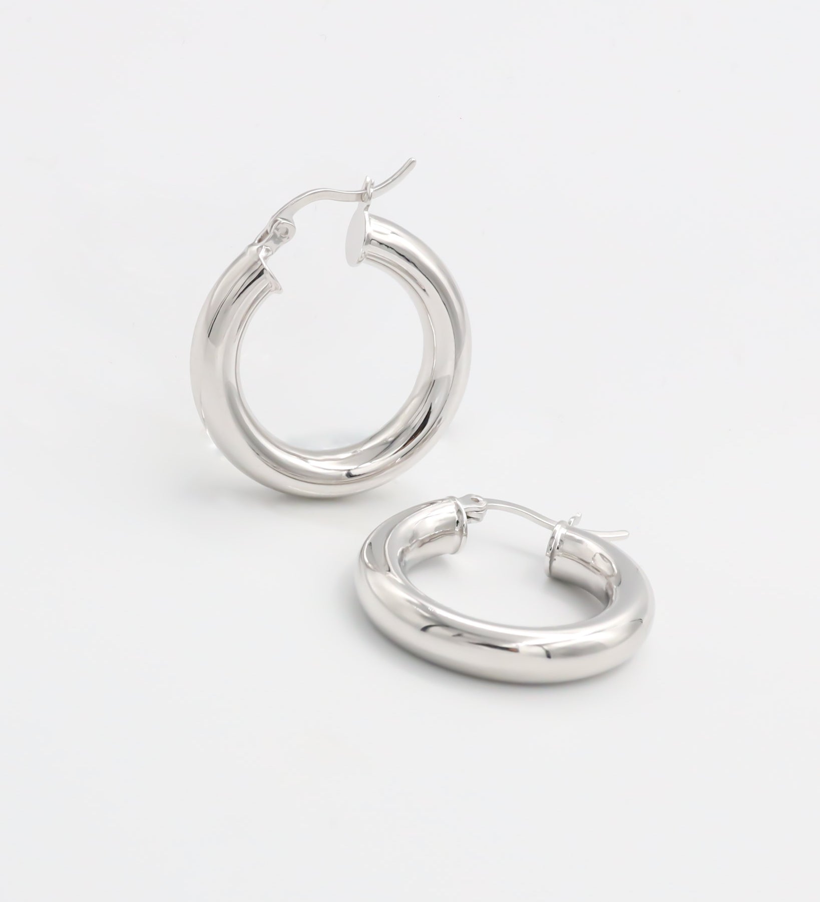 A pair of silver hoop earrings with a latch back closure, displayed against a white background.