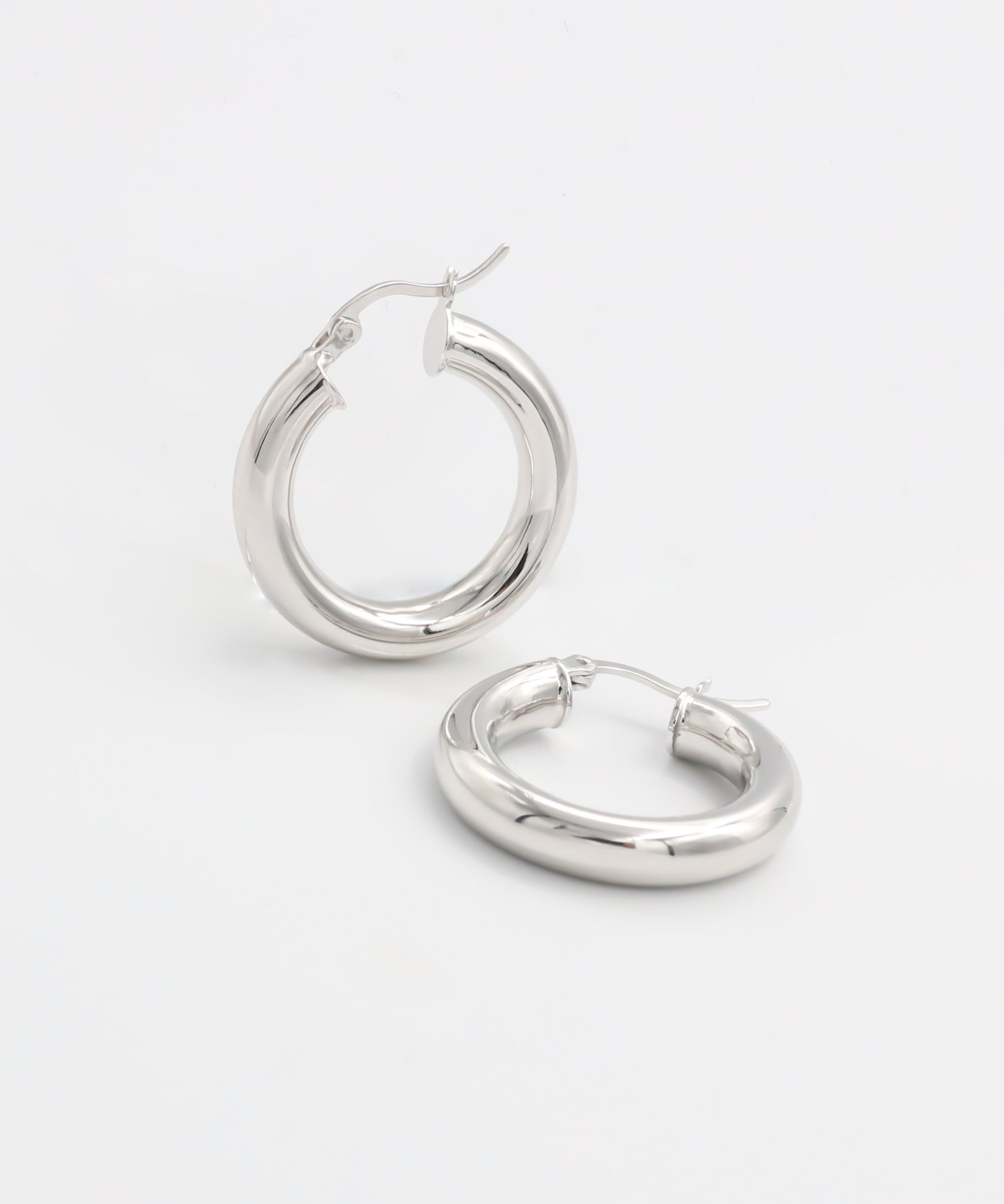 A pair of silver hoop earrings with a latch back closure, displayed against a white background.