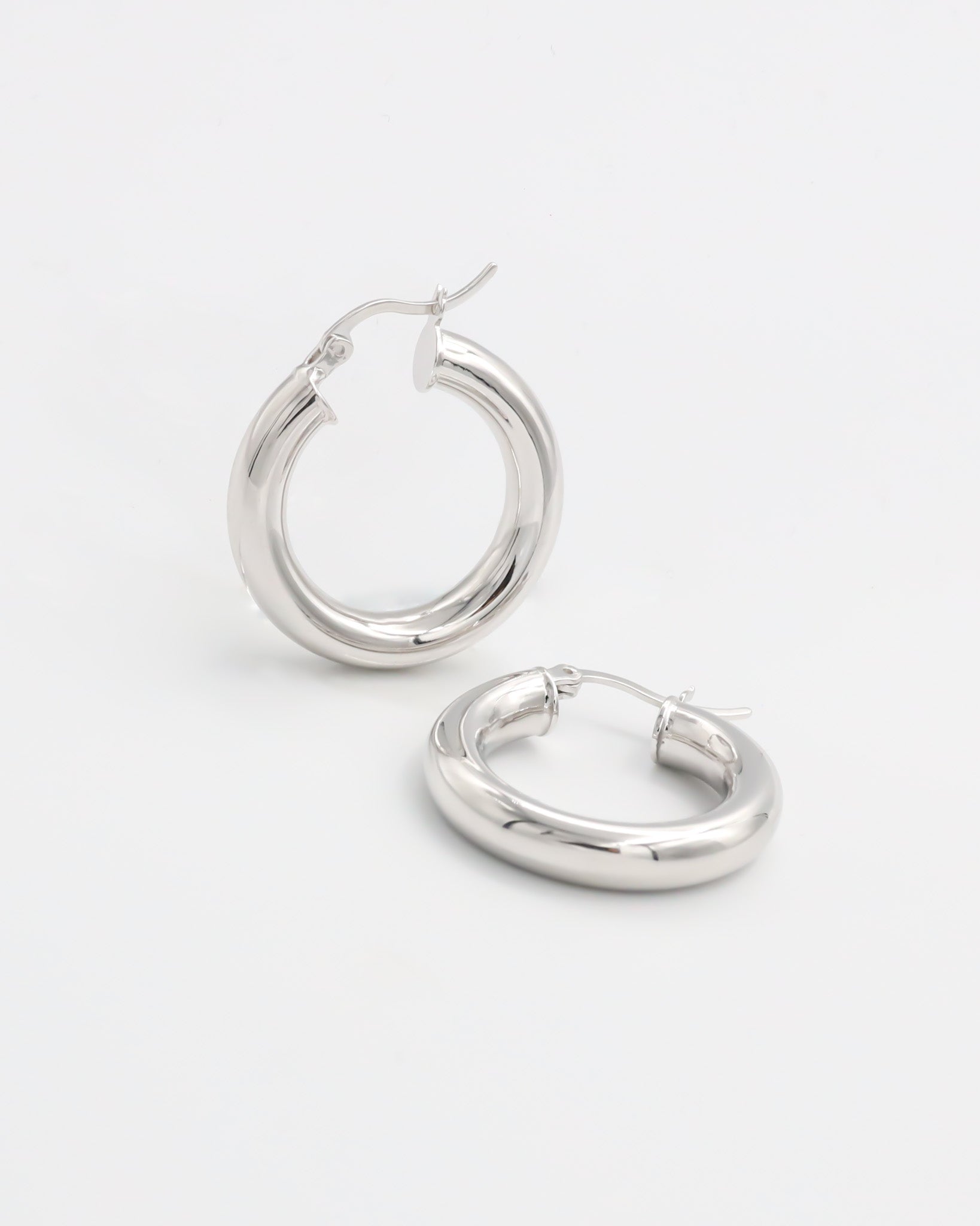 A pair of silver hoop earrings with a latch back closure, displayed against a white background.
