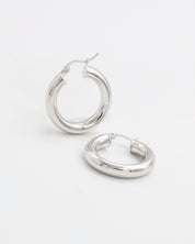A pair of silver hoop earrings with a latch back closure, displayed against a white background.