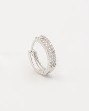 A pair of silver hoop earrings with a hinged clasp and small clear stones embedded around the hoop.