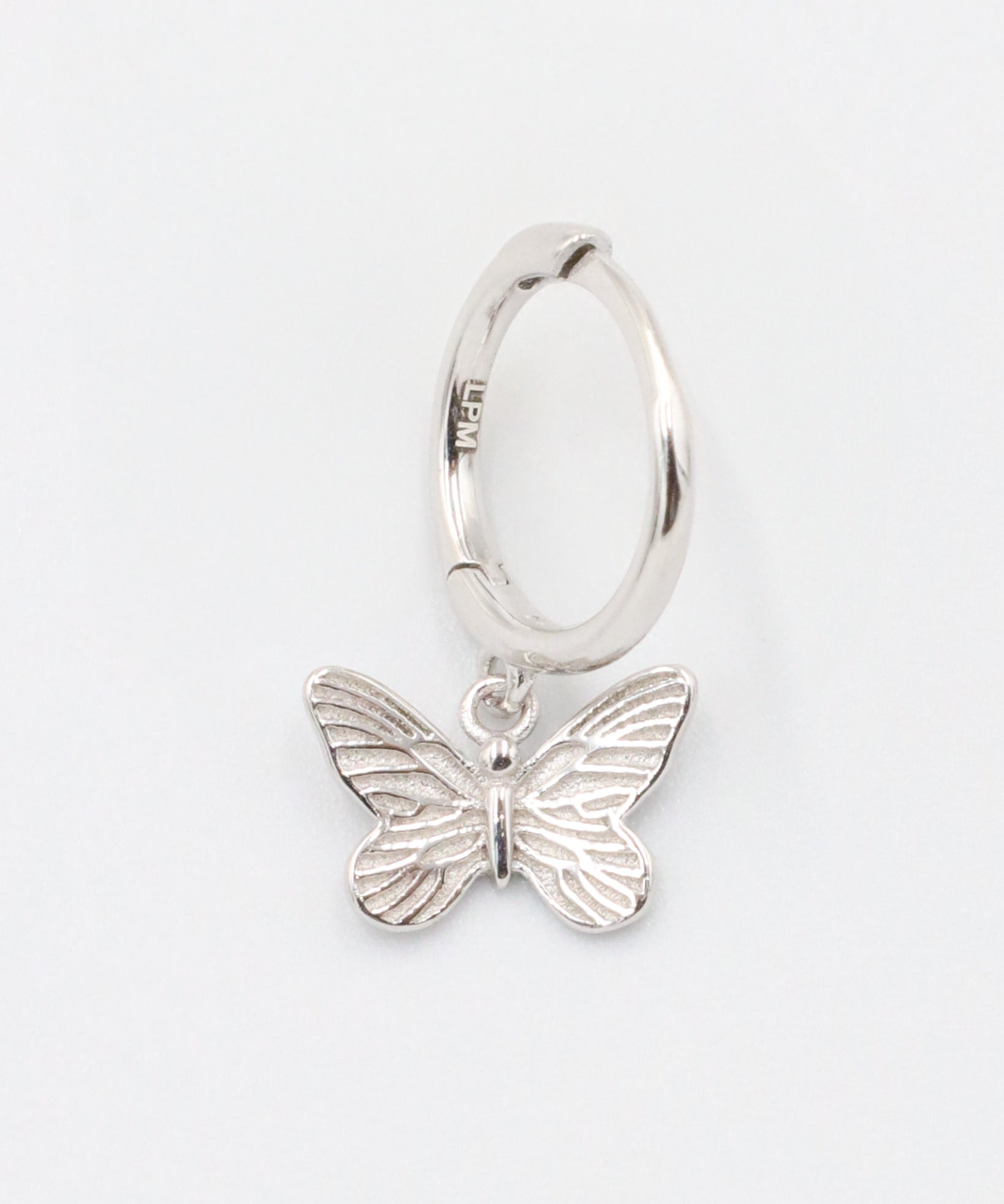 A silver hoop earring with a butterfly charm attached to it, displayed on a white background.