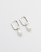 A pair of silver hoop earrings with pearl accents on a white background