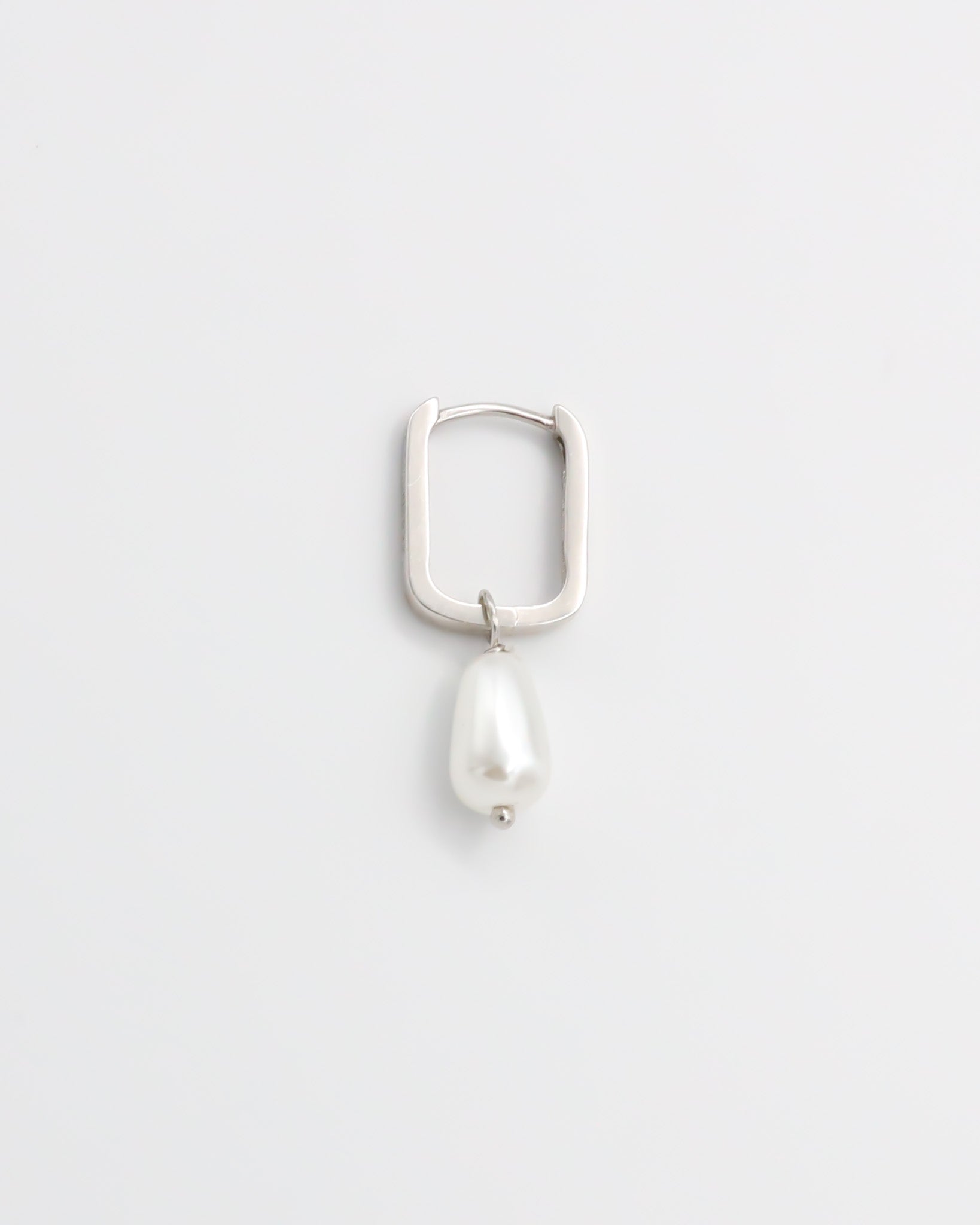 A single silver hoop earring with pearl accents on a white background