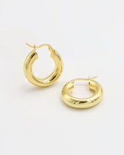 A pair of gold-colored hoop earrings with a latch back closure mechanism, displayed against a white background.