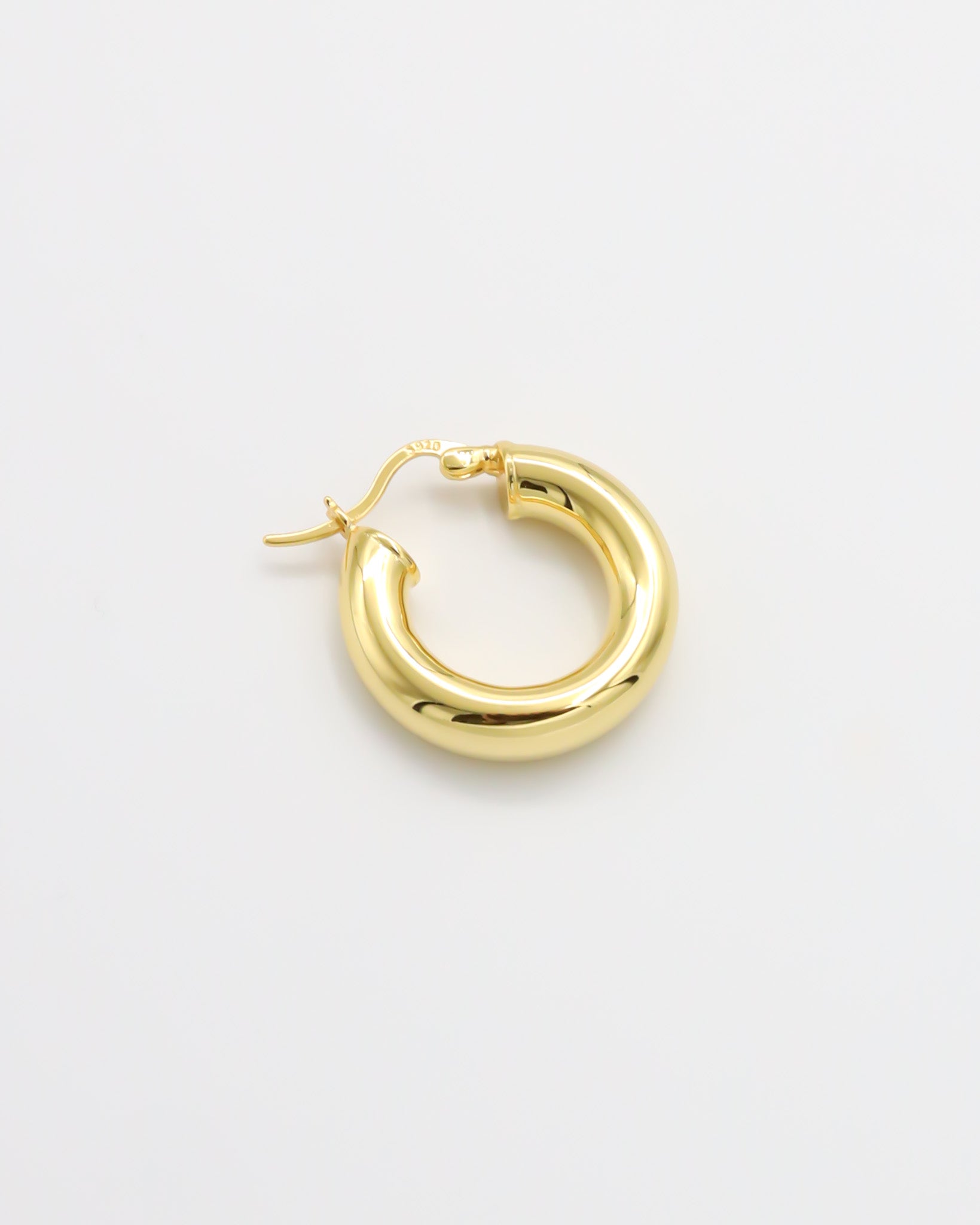 A single gold-plated hoop earring with a latch back closure mechanism, displayed against a white background.